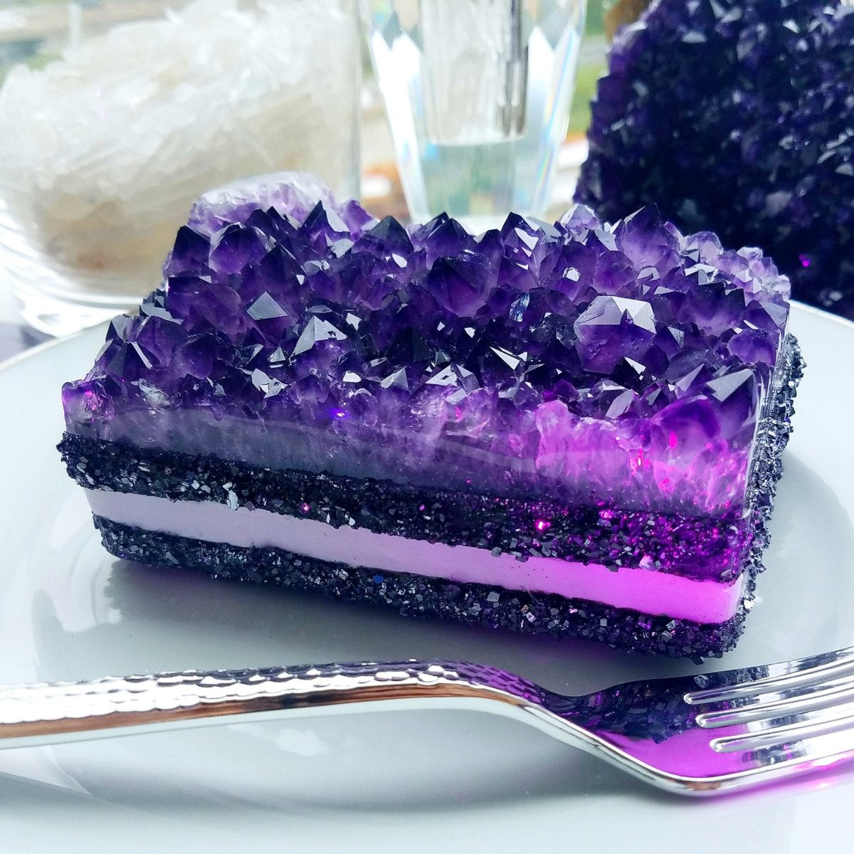 GemCake sculpture: a plated slice of amethyst geode over black and violet strata, served with a fork